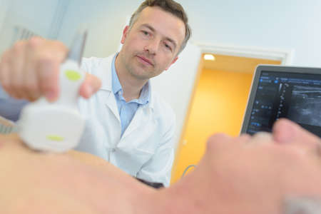 older man being scanned in doctors officeの写真素材