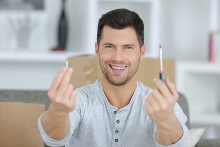 happy man showing a screwdriver and a screw