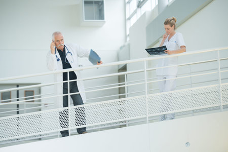 doctor nd nurse in hospital corridor resting against balconyの写真素材