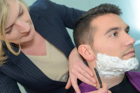 client during beard shaving in barber shop