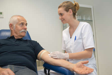 young woman doing blood test for senior man with diabetesの写真素材