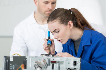 Woman using soldering iron to repair computerの写真素材