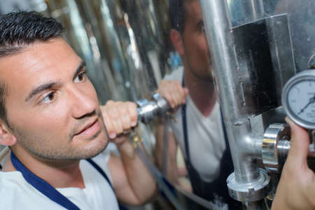 brewer testing beer from tank at breweryの写真素材