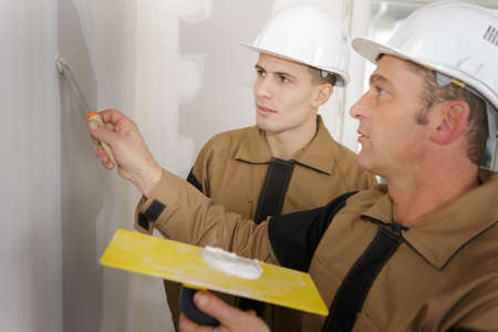 men plastering wall with spatula repair conceptionの写真素材
