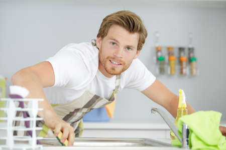 man cleaning kitchen furniture by yellow clothの写真素材