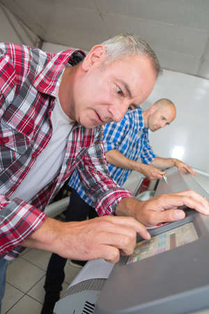 man working in printing house programming printer machineの写真素材