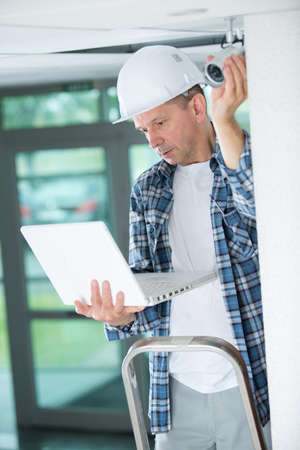 professional cctv technician working on laptopの写真素材