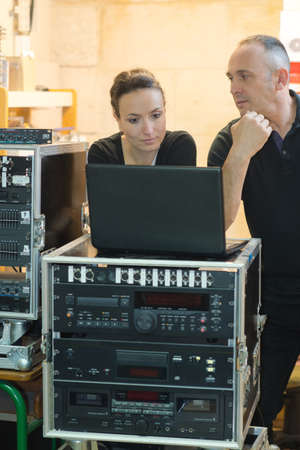 Crew looking at laptop connected to sound systemの写真素材