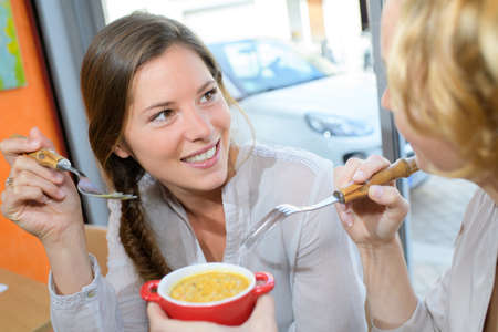 Women sharing from bowl of foodの写真素材