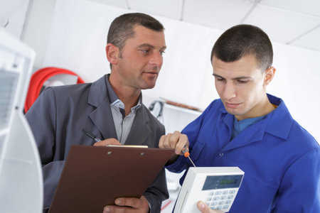 One man with clipboard, another using screwdriver