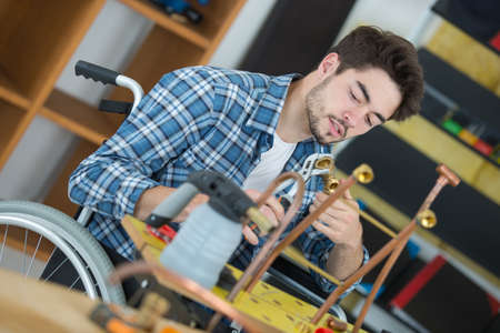 Handicapped man working with copper pipeの写真素材