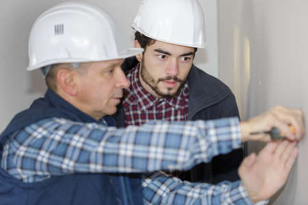 two electricians sockets installingat house construction siteの写真素材