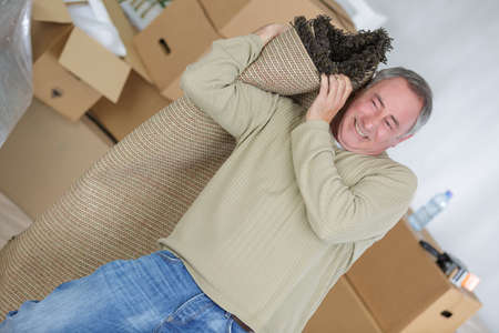 Man struggling to carry rugの写真素材
