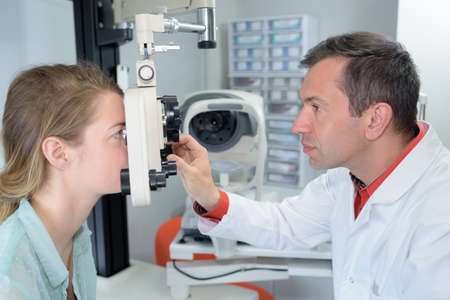 Optometrist aligning equipment to patient's faceの写真素材
