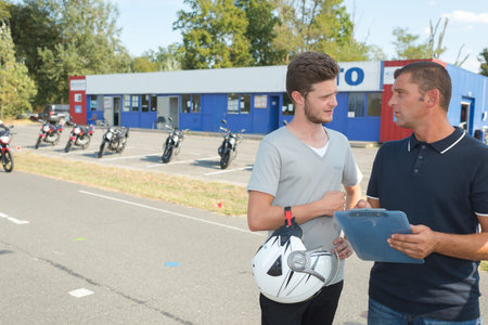 Young biker talking to instructor of motorcycle training course