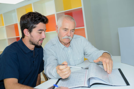 Two men looking through pages of folderの写真素材
