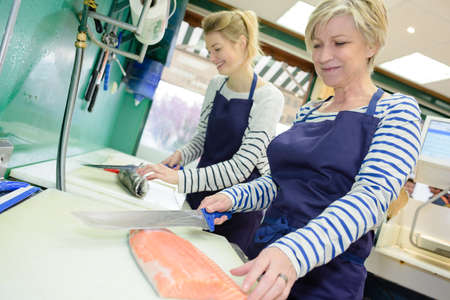 2 females preparing fish at fishmongersの写真素材