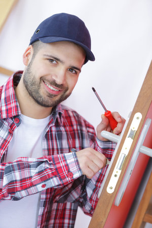 attractive young builder is installing doorlock