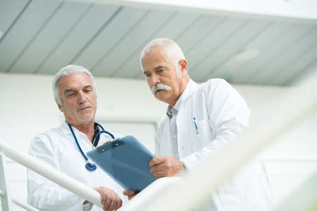 two doctors talking as they walk through modern hospitalの写真素材