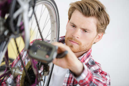 handsome young man repairing bike gear in his workshopの写真素材