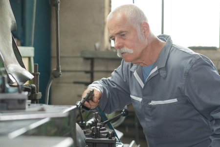 joyful mature man in apron working in locksmith