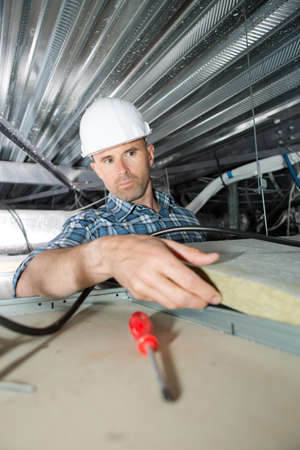 roofer builder worker installing roof insulation materialの写真素材