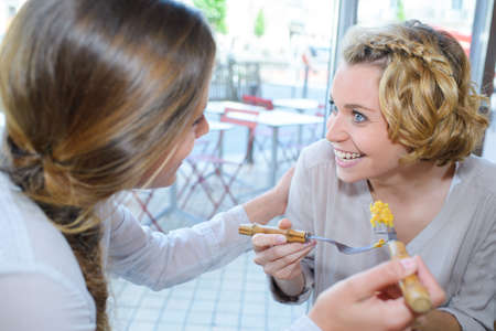 two women eating out in fast food restaurant talkingの写真素材