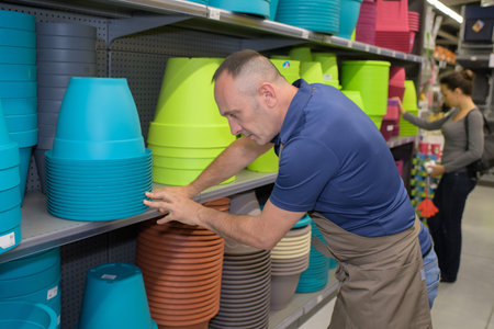 man tidying up colorful pots at a shopeの写真素材