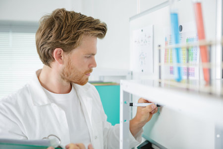 doctor holding a clipboard while writing on whiteboard