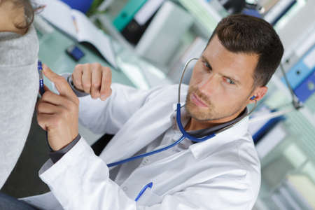 doctor checking male patients back with a stereoscopeの写真素材