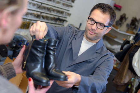 shoemaker giving shoes back to customerの写真素材