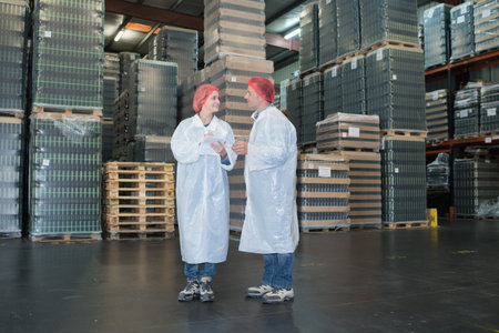 workers in white robe standing in a warehouse checking palletsの写真素材