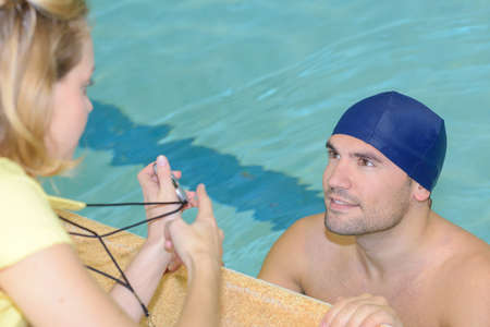 swimmer talking to his coach by poolside at leisure centerの写真素材