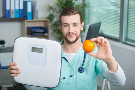 nurse holding fruit and weighing scaleの写真素材