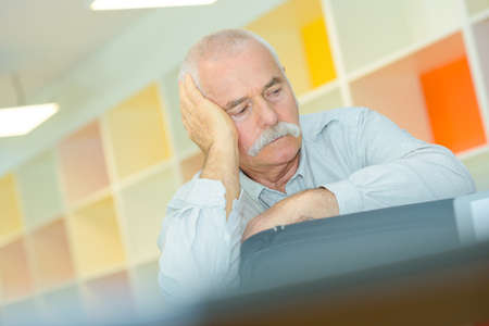 elderly man with hand on his temple has a headacheの写真素材
