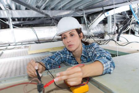 female electrician calibrating ceiling lampsの写真素材