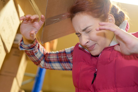 female worker hitting her head by accident into shelfの写真素材