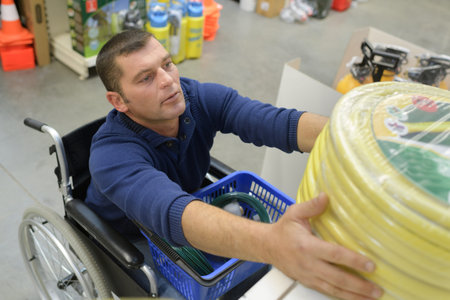 disabled man struggling to reach a hose at gardening store