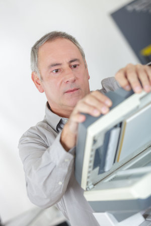 businessman hold ink cartridge to put into printerの写真素材