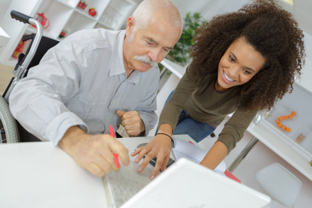 Senior man and young woman smiling and looking at laptop