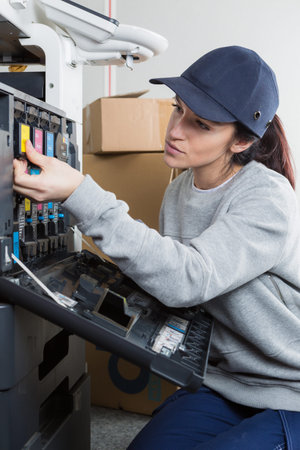 Female technician is repairing a printer at office