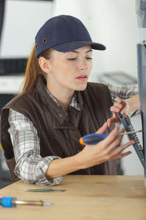 Young smiling brunette woman technician repairs a computerの写真素材