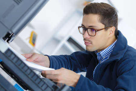 Man technician repairing a printer at business placeの写真素材