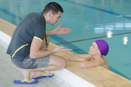 Swimming coach talking to swimmerの写真素材