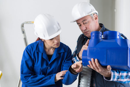 technician and apprentice working on ventilation pipes