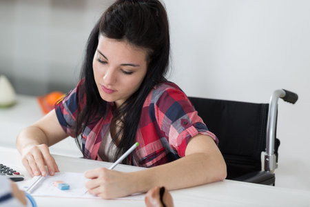 woman in wheelchair writing notes