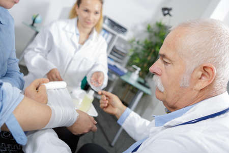 female and male doctor bandaging the arm of a patientの写真素材