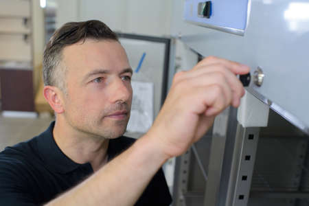 man is opening the cabinet with keysの写真素材