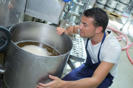 confident young male brewer checking beer maturation processの写真素材