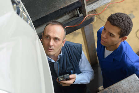 two mechanics repairing car in garage under the carの写真素材